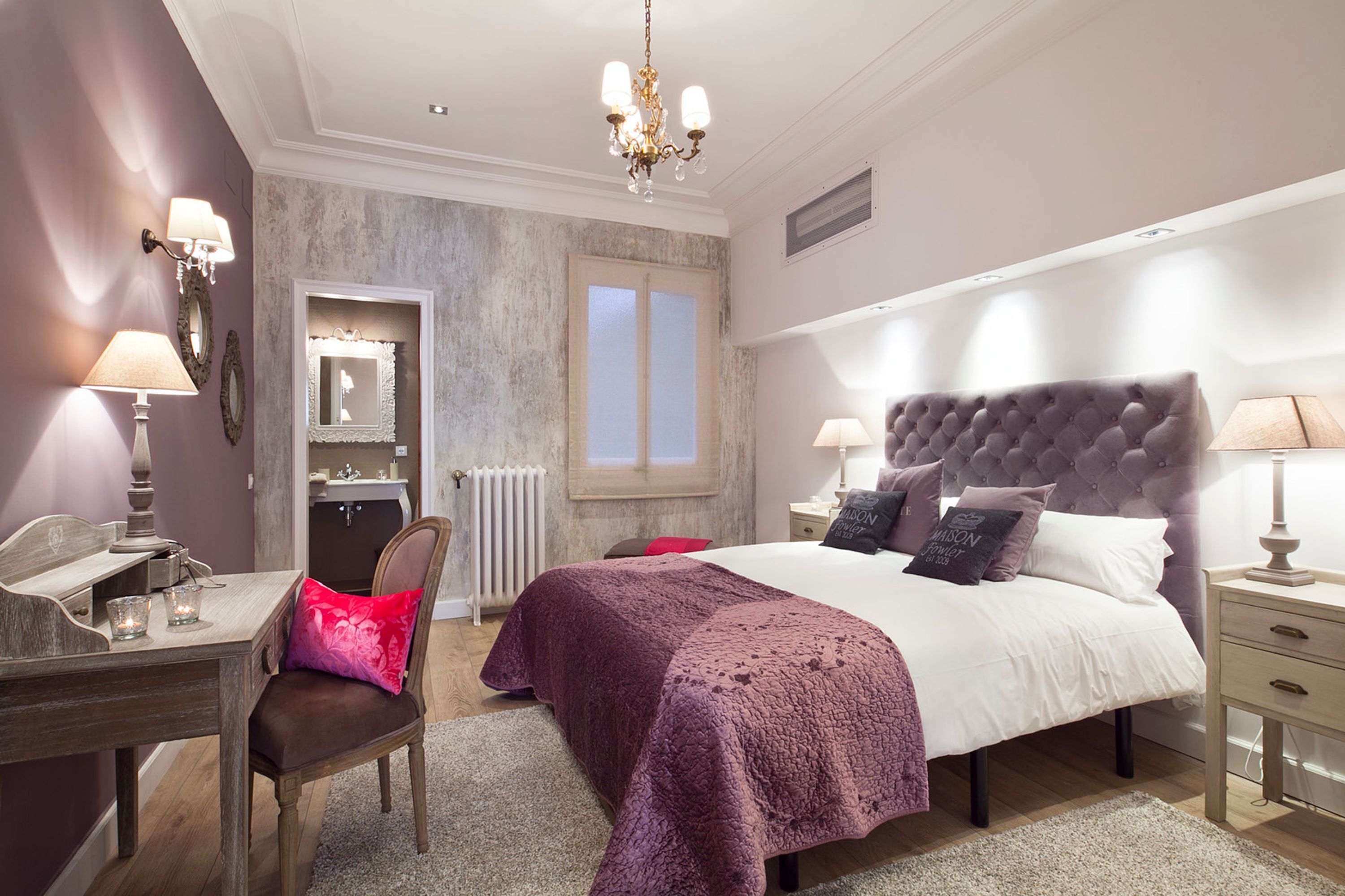 A bedroom with a large bed, bedside tables, a desk, and a chair.