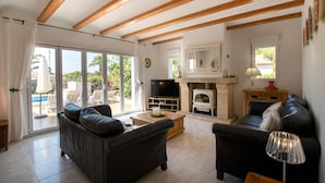 A living room with two sofas, a TV, a fireplace, and a large window with a view of the outdoors. - Villa Margarite in Javea (Javea)