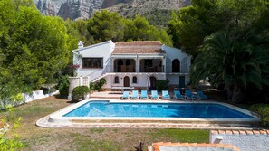 A two-story building with a swimming pool, outdoor seating, and a mountainous backdrop. - Villa Rosa in Javea With 4 Bedrooms and 3 Bathrooms (Javea)