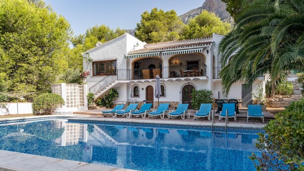 Ein zweistöckiges Gebäude mit Pool und Liegestühlen.