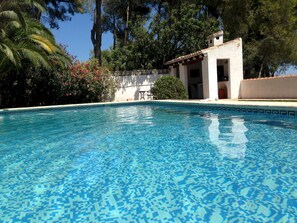 A clear blue pool with a tiled pattern, surrounded by lush greenery and a small building with an arched doorway. - Villa Rosa in Javea With 4 Bedrooms and 3 Bathrooms (Javea)