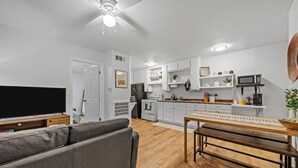 A modern living room with a grey sofa, wooden dining table, and a flat-screen TV. - Flint A (Waco)