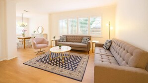 Un salon avec un canapé beige, une table basse ronde et un tapis à motifs.
