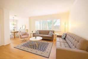 A living room with a beige sofa, a round coffee table, and a patterned rug. - Allura Carmel Valley - 4 BR 4 BA (San Diego)