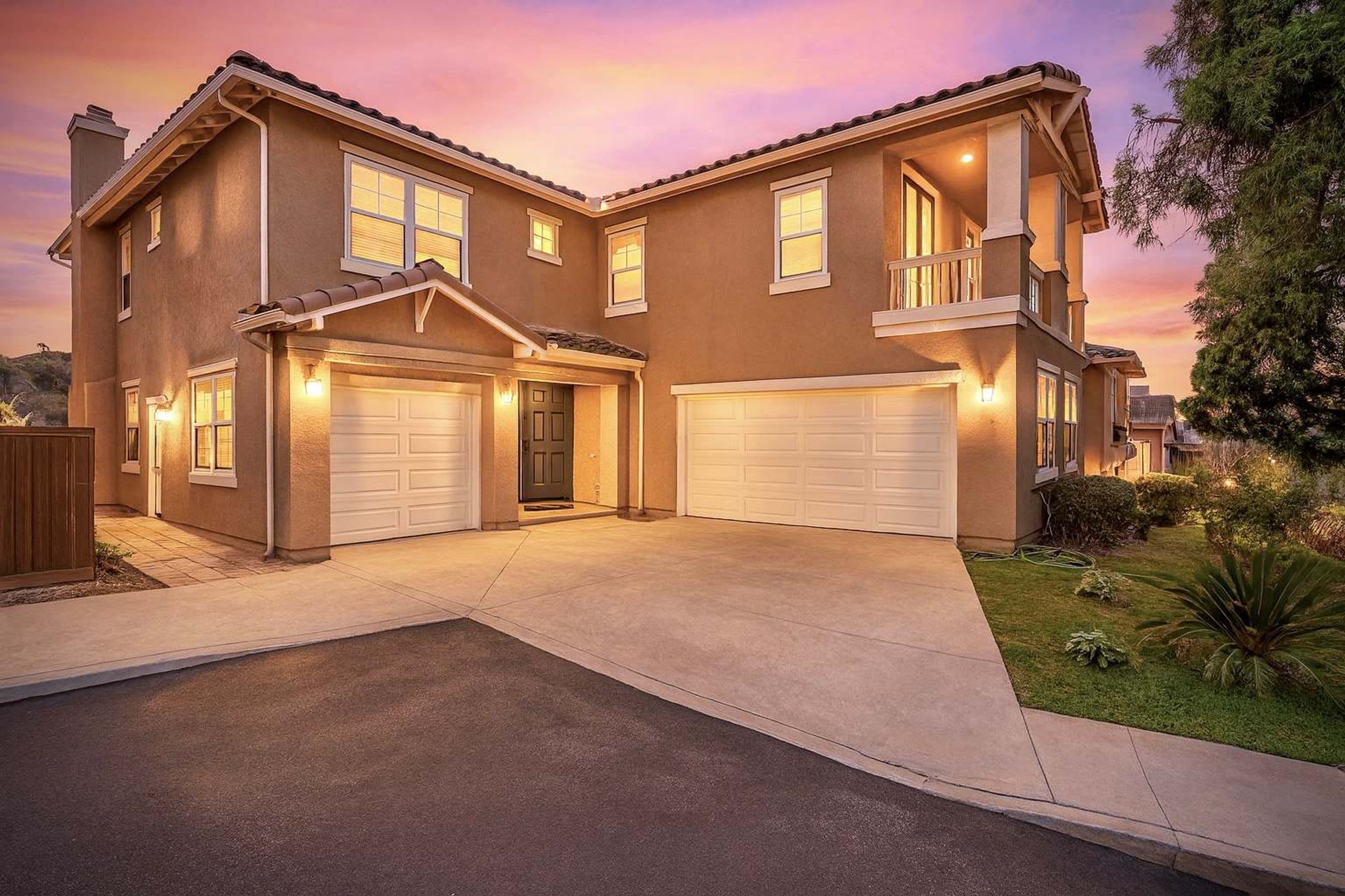A two-story house with a garage, a balcony, and a well-maintained lawn.