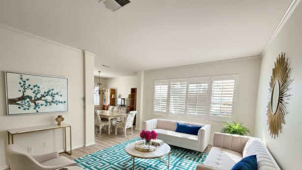 A spacious living room with a dining area, white furniture, and a blue patterned rug.