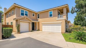 A two-story house with a garage, a small front porch, and a well-maintained lawn.