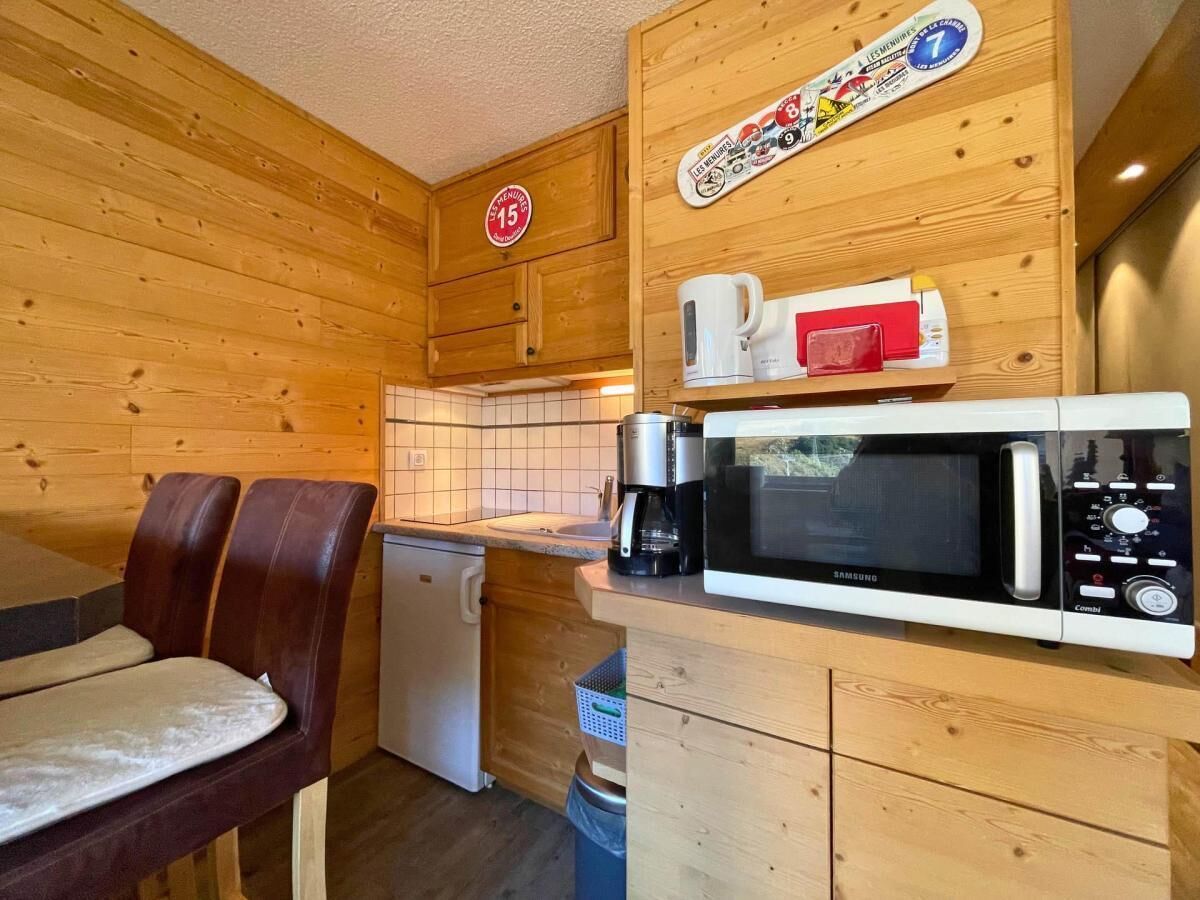 Eine kleine Küche mit Holzwänden, einer Mikrowelle, einer Kaffeemaschine und einem kleinen Kühlschrank.