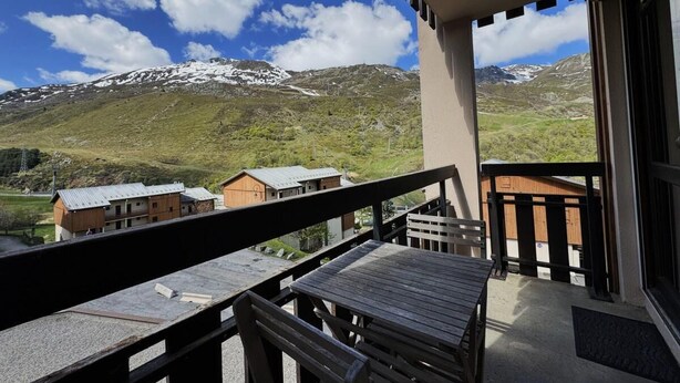Un balcón con vistas a montañas nevadas y un cielo azul despejado.