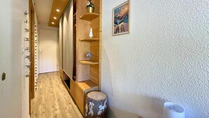 Un pasillo con suelo de madera, un banco de madera, un pequeño árbol de Navidad y un cuadro en la pared.