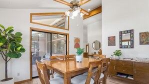 Un comedor con una mesa y sillas de madera, un ventilador de techo y una planta en maceta.
