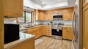 Una cocina moderna con gabinetes de madera, electrodomésticos de acero inoxidable y encimera de granito.