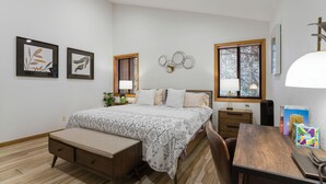 Un dormitorio con cama, mesitas de noche, escritorio y silla.