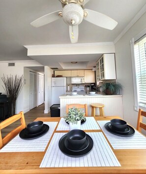A modern kitchen with white cabinets, a central island, and a ceiling fan.