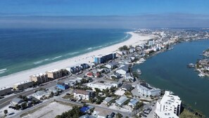 An aerial view of a coastal town with a beach, marina, and residential buildings.