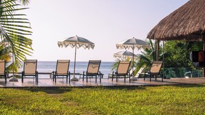 En avslappnad lounge vid stranden med stolar och parasoller, med utsikt över havet.