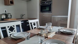 A modern kitchen with a dining area set for four. - The magnolia (Hautot-sur-Mer)