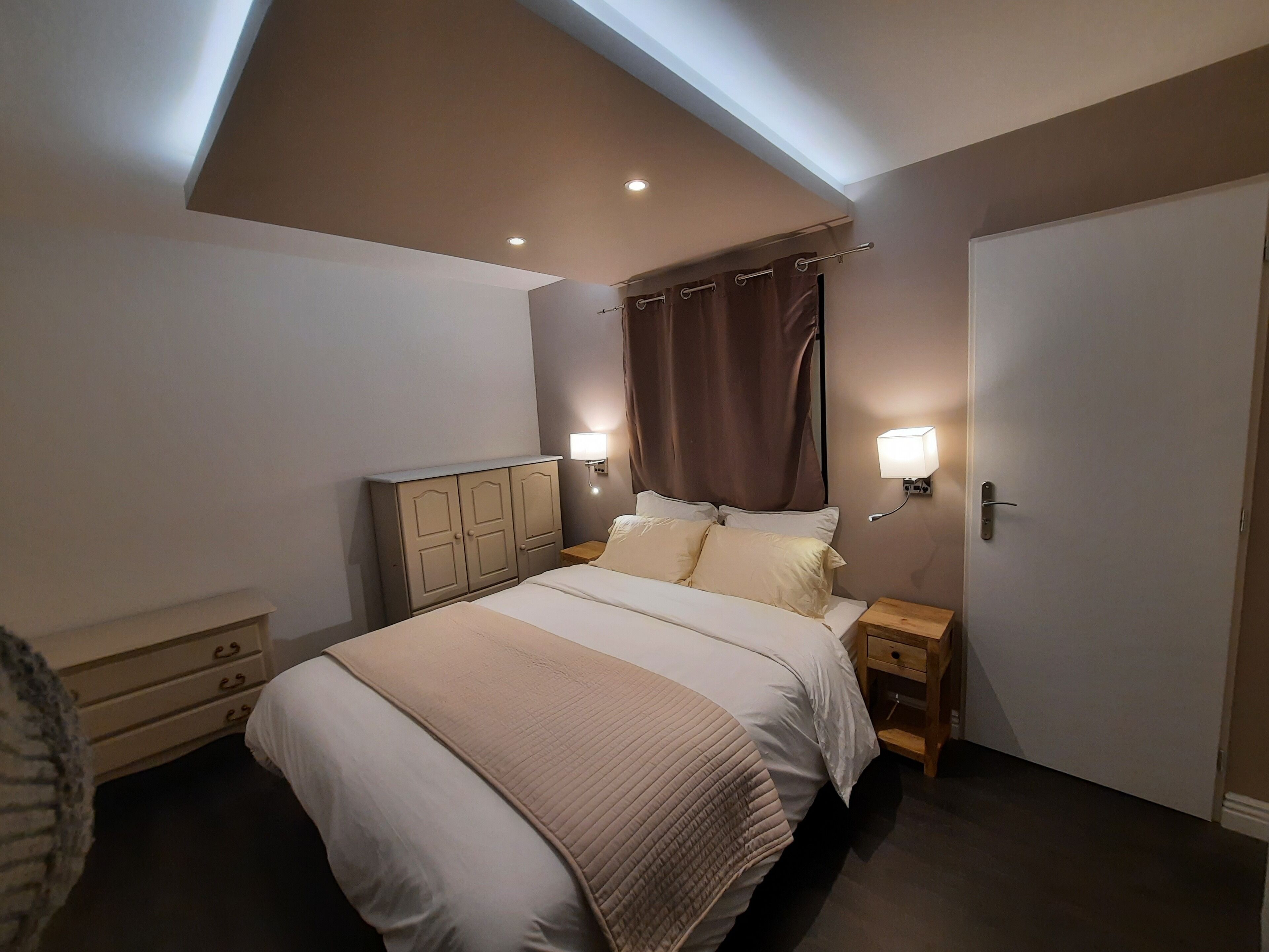Une chambre à coucher avec un lit, des tables de chevet, une armoire et une lucarne.
