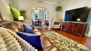 A living room with a brown leather sofa, a patterned rug, a television, and a dining area in the background. - *Port Clinton*3 BedRM*SunRM*Fenced Yard*Near Beach/Park/Lighthouse/Restaurants* (Port Clinton)