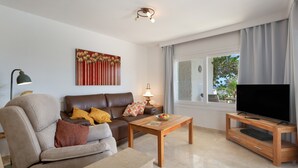 Ein Wohnzimmer mit Sofa, Couchtisch, einer TV-Konsole und Kunstwerken an der Wand.