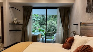 Un dormitorio con una cama grande, vistas a zonas verdes y una pequeña mesa con sillas.