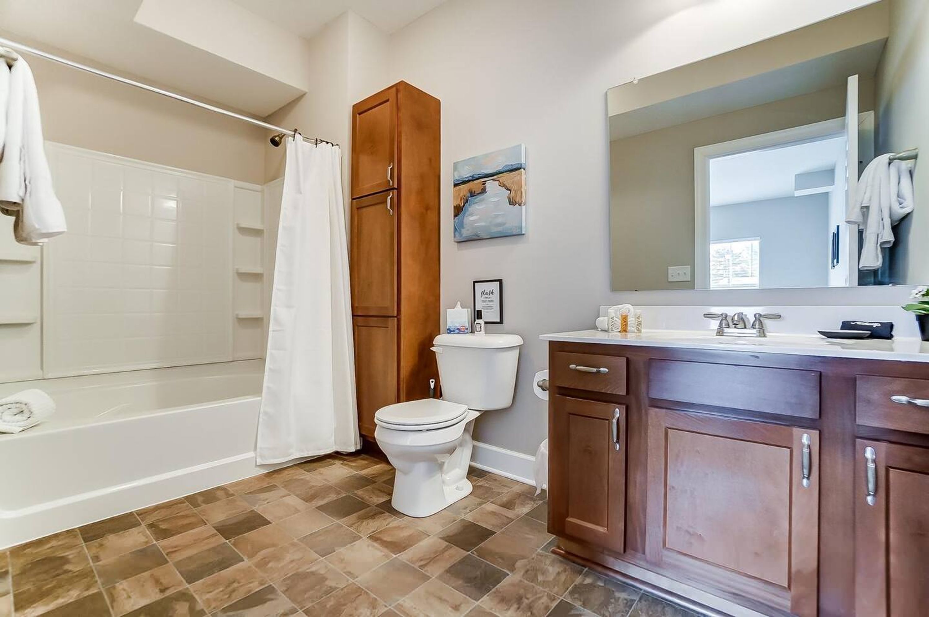 A bathroom with a bathtub, toilet, and wooden cabinets.
