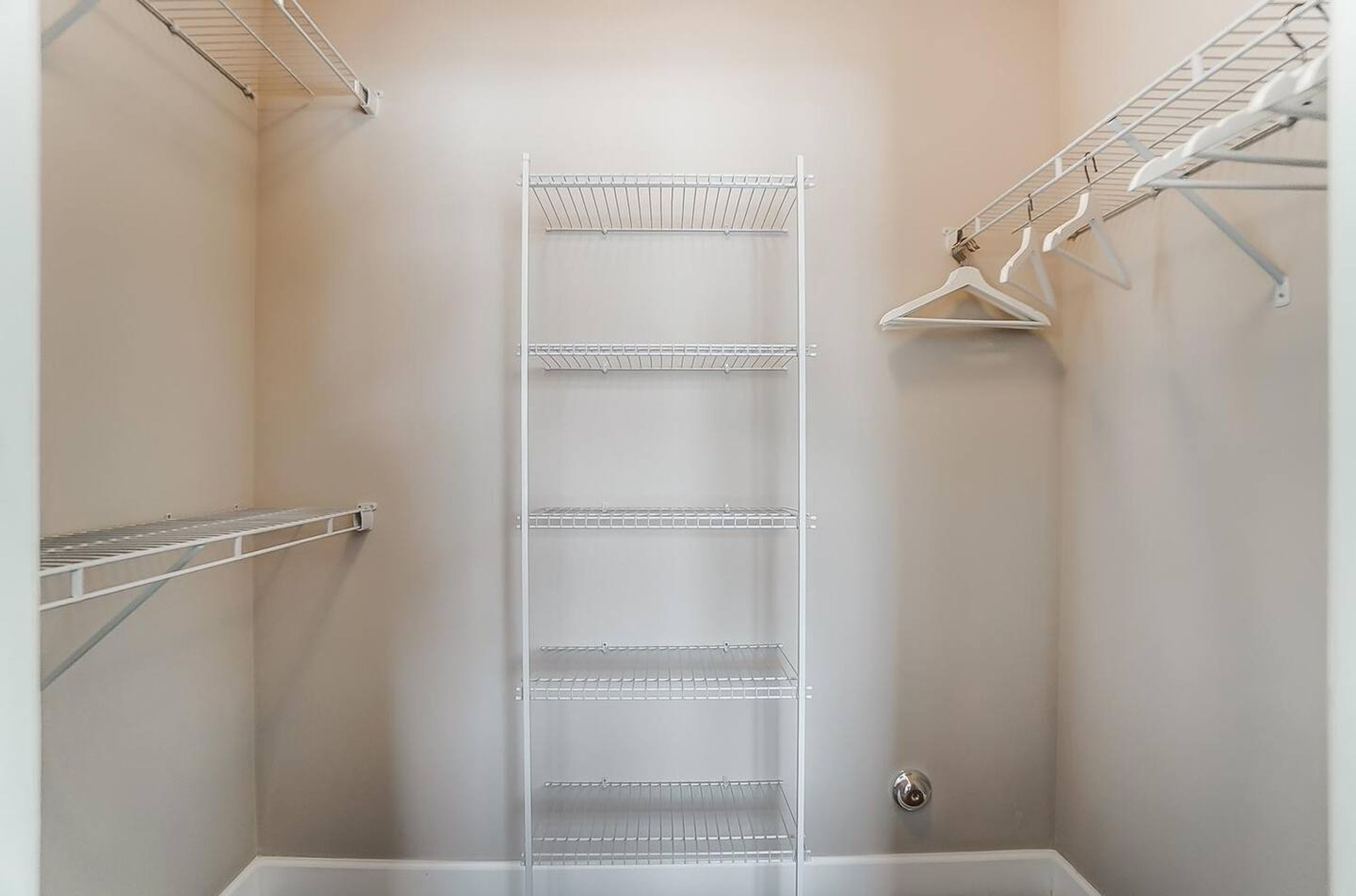 Um closet amplo com prateleiras de metal e uma barra para pendurar roupas.