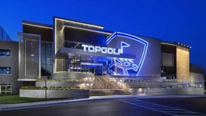Un edificio moderno con un gran letrero iluminado que dice "TOPGOLF".