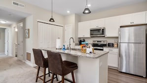 A modern kitchen with white cabinets, stainless steel appliances, and a granite countertop. - Powell Retreat Attached Garage Walk-in Shower (Powell)