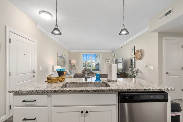 A modern kitchen with granite countertops, a stainless steel dishwasher, and pendant lighting. - Powell Retreat Attached Garage Walk-in Shower (Powell)