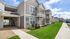 A row of townhouses with a covered garage, a small front yard, and a clear sky. - Powell Retreat Attached Garage Walk-in Shower (Powell)