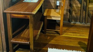 A wooden room with a desk and chair, a small shelf, and a green curtain. - Green Jay Cabin 2 (Cristo Rey)