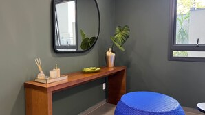 Une salle de bain moderne avec un meuble-lavabo en bois, un miroir, une plante en pot et un tabouret bleu tissé.