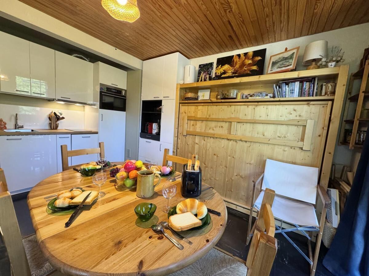 Un coin repas avec une table en bois mise pour le petit-déjeuner, comprenant des croissants, des fruits et une cafetière.