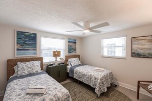 Ein Schlafzimmer mit zwei Betten, einem Deckenventilator und Kunstwerken an den Wänden.