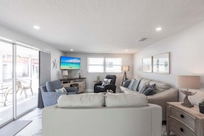 A modern living room with a sofa, a TV, and a dining area with a table and chairs.