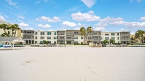 Ein Hotel direkt am Strand mit mehreren Etagen, Balkonen und einem Sandstrand davor.
