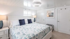 Ein Schlafzimmer mit einem Bett, Nachttischen, einem Kleiderschrank und einem Fenster mit Jalousien.