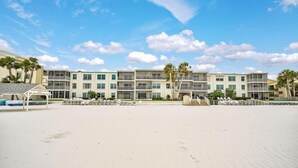 Un hotel frente a la playa con varios pisos, balcones y una zona de arena.