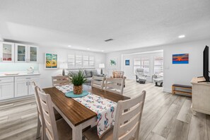 A spacious living area with a dining table, chairs, and a sofa.