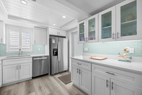 A modern kitchen with white cabinetry, a stainless steel refrigerator, and a tiled backsplash.