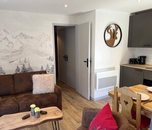 A modern living room with a sofa, a dining table, and a kitchen area with cabinets and a stove. - 230m from shops, 3rd floor, view valley, balcony, tv, 33m², Méribel-Mottaret (Méribel - Les Allues)