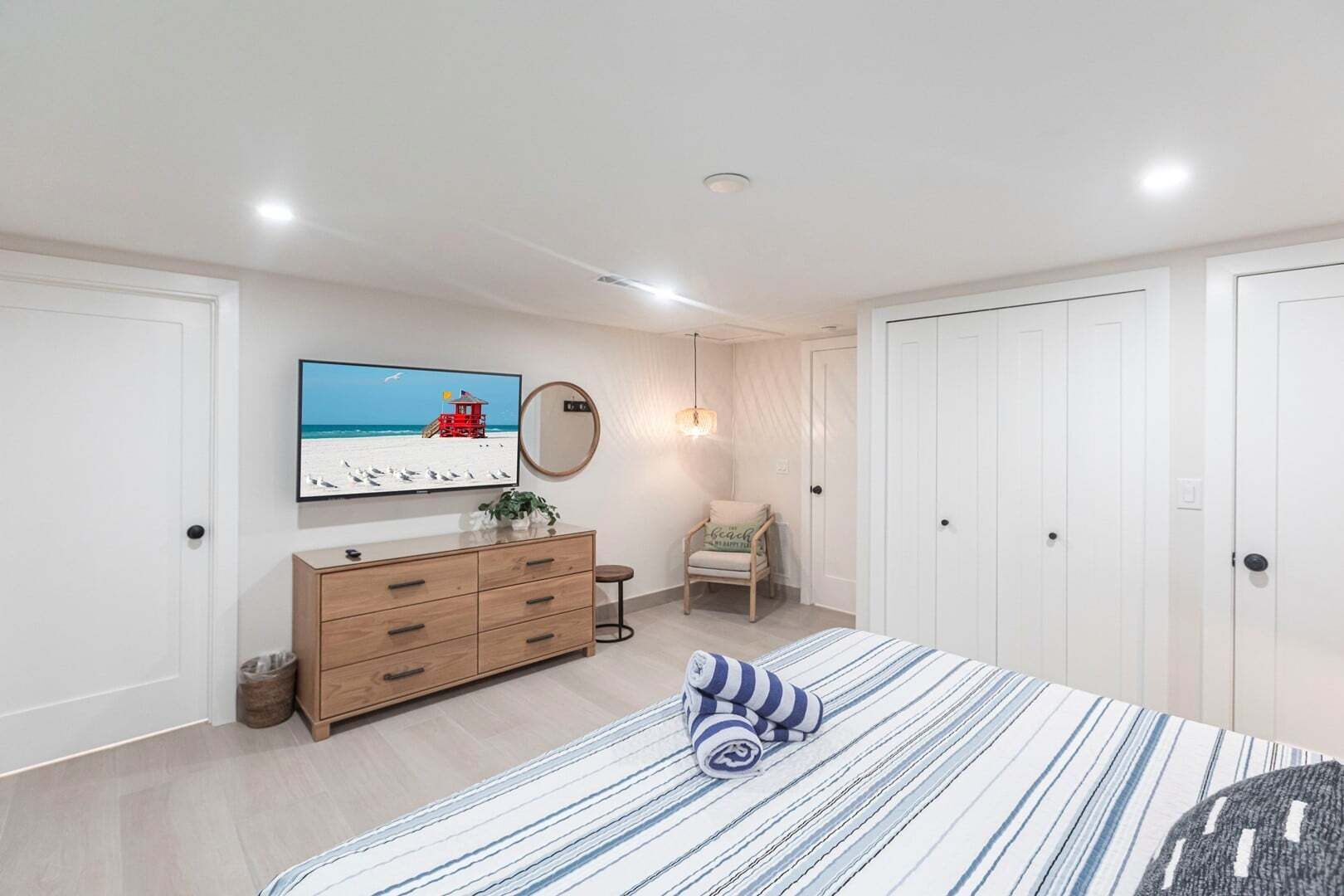 Une chambre à coucher comprenant un lit, une commode, un téléviseur, une chaise et une armoire.