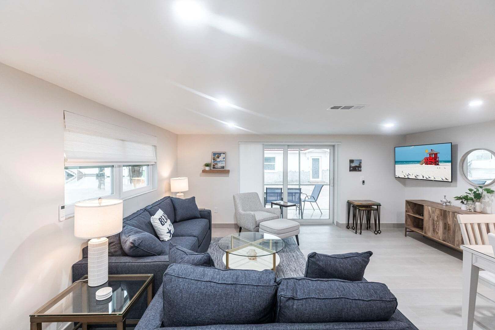 A modern living room with a sofa, armchair, and glass coffee table.