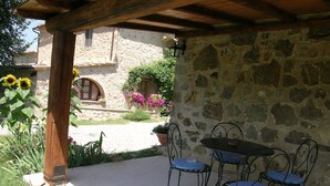 A covered patio with stone walls, a table, and four chairs. - Agriturismo Bellavista between Amiata and Val dórcia - Mountain apartment (Toscana)