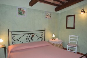 A bedroom with a bed, a chair, a small table with a lamp, and two wall-mounted picture frames. - Agriturismo Bellavista between Amiata and Val dórcia - Mountain apartment (Toscana)