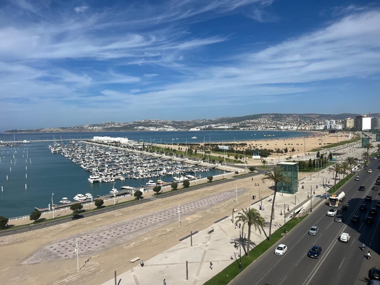 Ein Küstenort mit Booten, einem Strand und einer Straße mit Fahrzeugen.