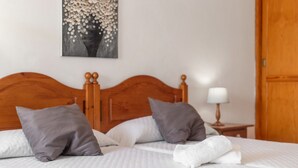 A neatly made bed with a wooden headboard, two pillows, a white blanket, and a painting on the wall. - Studio 'Martin - 21' with Sea View, Balcony and Wi-Fi (Puerto de Naos)