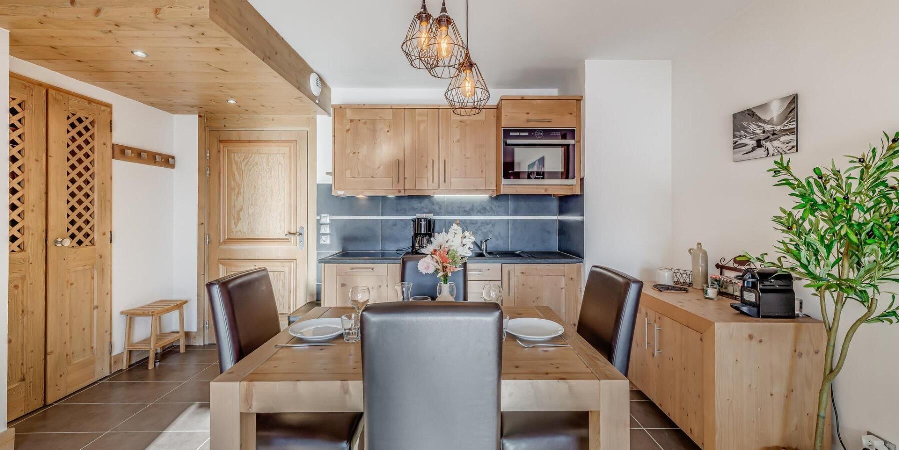 A modern kitchen with wooden cabinets, a dining table with chairs, and a coffee machine.