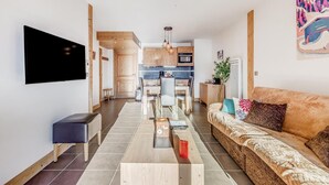 Ein modernes Wohnzimmer mit einer Couch, einem Couchtisch und einem an der Wand befestigten Fernseher.
